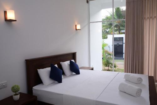 a bedroom with a bed with blue and white pillows at The Ritz Hikkaduwa in Hikkaduwa