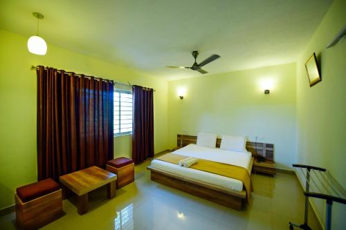 a bedroom with a bed and a chair and a window at Shesha KUTEERA in Subrahmanya