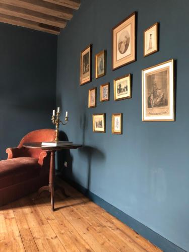 a room with a blue wall with a chair and framed pictures at ZONE BLEUE in Hyds