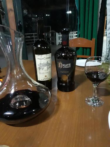 duas garrafas de vinho e um copo sobre uma mesa em Resort Te Zagolli em Orikum