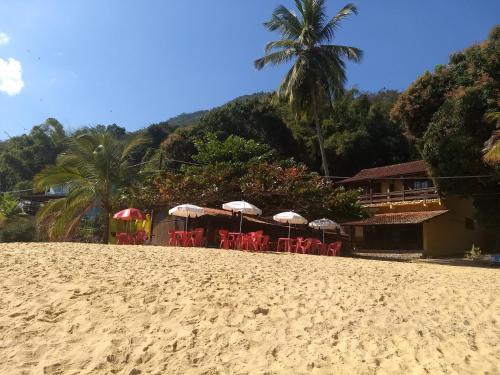 a beach with some chairs and umbrellas on it at Pousada Tony Montana in Praia de Araçatiba