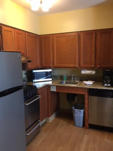 a kitchen with wooden cabinets and a sink and a refrigerator at Hawthorn Extended Stay by Wyndham Cincinnati NE Mason in Mason