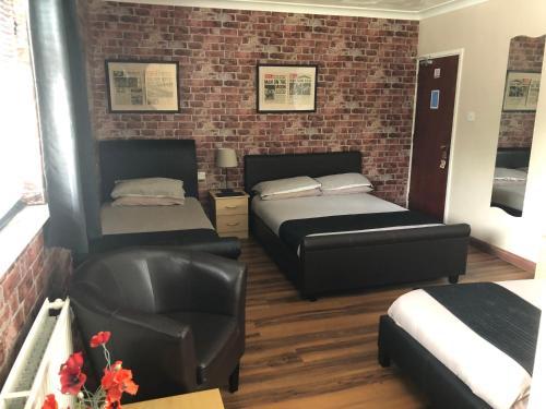um quarto de hotel com duas camas e uma cadeira em Lakeland Guest House em Pembroke Dock