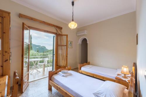 a room with two beds and a balcony at Villa Maria Makri in Paleokastritsa