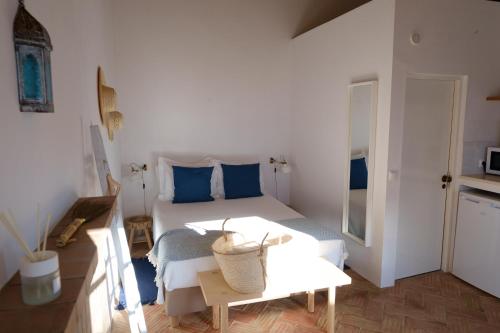 Casas de Mértola 32 في ميرتولا: غرفة نوم بسرير ومخدات زرقاء وطاولة