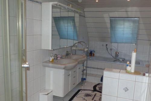 W łazience znajduje się umywalka, lustro i wanna. w obiekcie Ferienwohnung Schelhorn w mieście Mengersgereuth-Hämmern