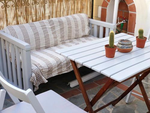 a white table and a couch on a porch with cactus at Dominik apartment in Patmos