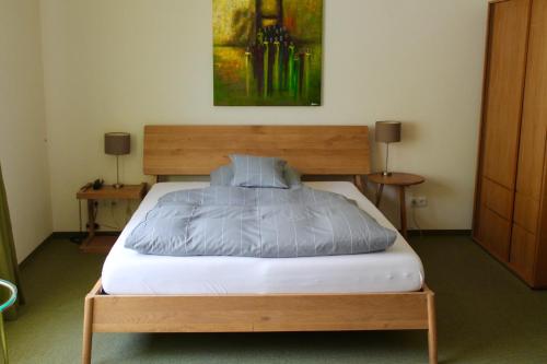 ダルムシュタットにあるホテル ドナースベルクのテーブル2台と絵画が備わる部屋のベッド1台