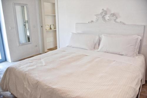 a white bed with white sheets and pillows at Borgo Santa Clara in Cisternino