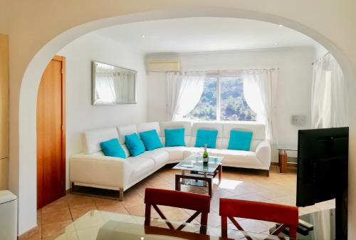 a living room with a white couch and blue pillows at Villa Guapa With Gym Aircon Wifi Moraira in Moraira
