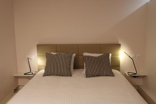 a bedroom with a bed with two pillows and two lamps at Strasbourg Entzheim in Entzheim