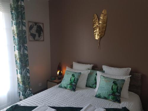 a bedroom with a bed with green and white pillows at Le Clos Magedon in Médan