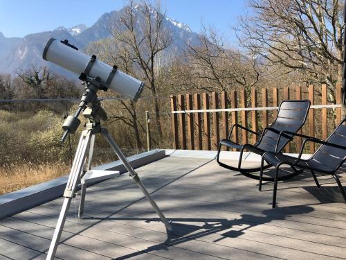 a telescope on a deck with two chairs at Swiss Lake Lodge in Noville