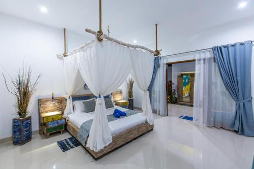 a bedroom with a canopy bed with white drapes at MasBro ART Villas in Seminyak