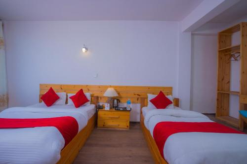 two beds in a room with red pillows at Mount Princess Hotel in Dhulikhel