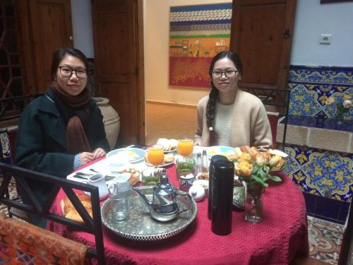 deux femmes assises à une table avec un tissu de table rouge dans l'établissement Dar Halima, à Essaouira