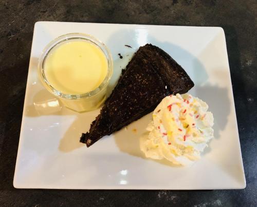a white plate with a piece of cake and a drink at Hôtel-Restaurant Le Blueberry in Malaucène