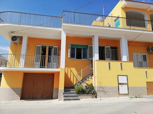 a yellow house with a balcony and stairs at Case Vacanze Profumo Di Mare in Scicli