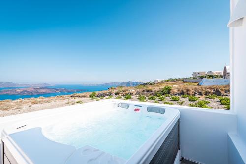 a hot tub on a balcony with a view of the ocean at Caldera Stories private suites in Megalokhori