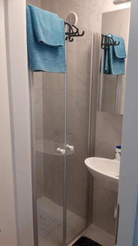 a bathroom with a shower with a sink and blue towels at Orange Cube Apartment - Self check in - Free parking in Rijeka