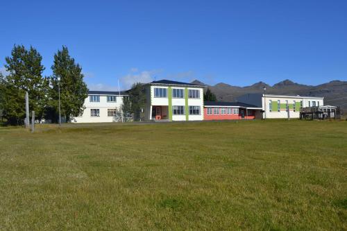 un gran campo de césped frente a un edificio en Hotel Stadarborg, en Breiðdalsvík