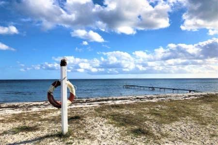 a white pole with a life preserver on a beach at Cosy little guesthouse near beach & public transport in Greve Strand