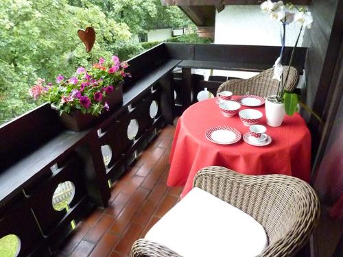 a balcony with a red table and chairs and flowers at Ferienappartment Zürker in Garmisch-Partenkirchen