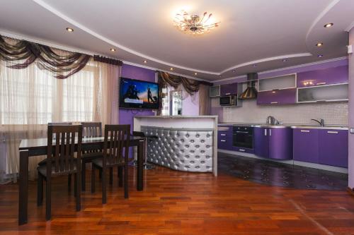 cocina con armarios morados, mesa y sillas en Заливна вулиця 5, en Sumy