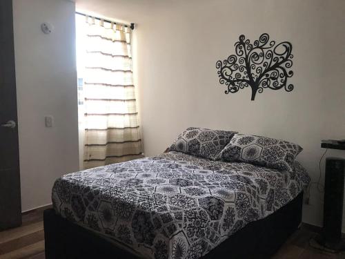 a bedroom with a bed and a tree on the wall at Apartamento vacacional Ibagué in Ibagué