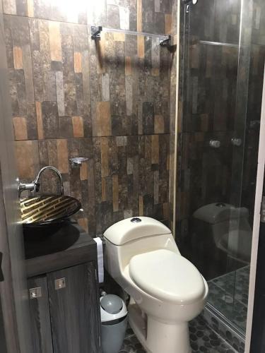 a bathroom with a toilet and a glass shower at Apartamento vacacional Ibagué in Ibagué