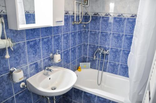 Zvekir - Old Town Apartment في سراييفو: حمام من البلاط الأزرق مع حوض استحمام وحوض استحمام