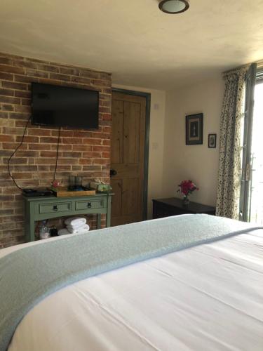 een slaapkamer met een tv aan een bakstenen muur bij The Tea House in Rye