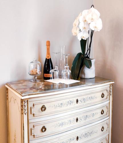 a dresser with a bottle of champagne and a vase of flowers at Ilsanleonardo in Bergamo