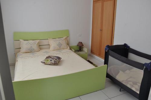 a green bed with a pillow on it in a bedroom at Apartment zone touristique 80 m beach free wifi in Mahdia