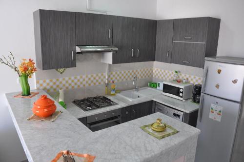 a kitchen with a stove and a sink and a refrigerator at Apartment zone touristique 80 m beach free wifi in Mahdia