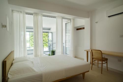 a bedroom with a bed and a desk and windows at City Centre Rooms in Limassol