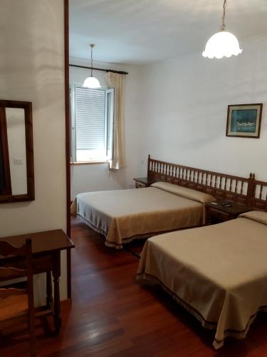 a hotel room with two beds and a window at HOSTAL RESIDENCIA PRESIDENTE in Ribadeo