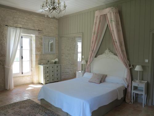 a bedroom with a white bed with a canopy at Le Moulin de la Borderie in Saint-Pierre-dʼOléron