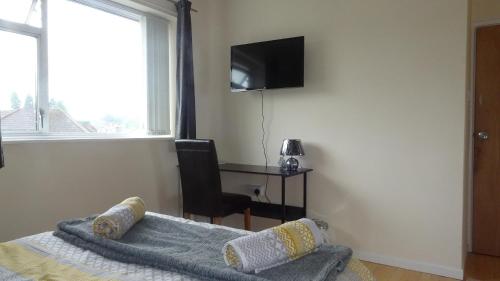 a bedroom with a bed and a desk and a television at St Margaret's House in Leamington Spa