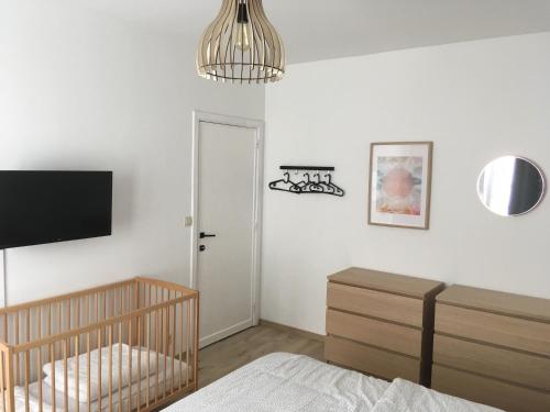 a bedroom with a crib and a tv on the wall at « Les 3 Moussaillons » appartement 2 ch Coxyde in Koksijde
