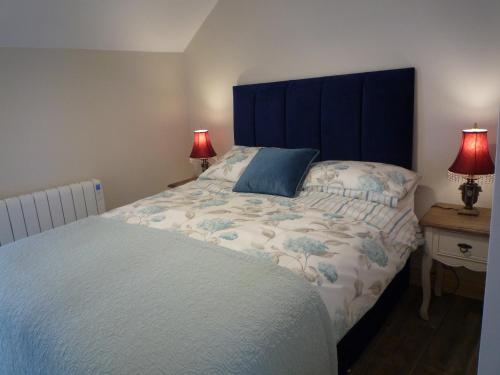 a bedroom with a bed with a blue headboard and two lamps at Kitty's in Tullamore