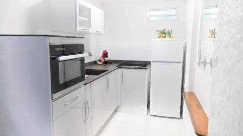 a white kitchen with white cabinets and appliances at Ocean BAYALOCATION in LʼAnse Mitan