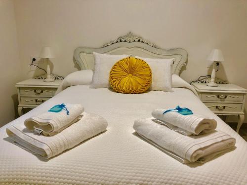 ein Schlafzimmer mit einem Bett mit Handtüchern und zwei Nachttischen in der Unterkunft Apartamentos Turísticos Casa Dina in Rinlo