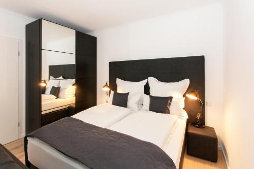 - une chambre avec un grand lit et un miroir dans l'établissement Main Apartment Frankfurt Neu Isenburg, à Neu-Isenburg