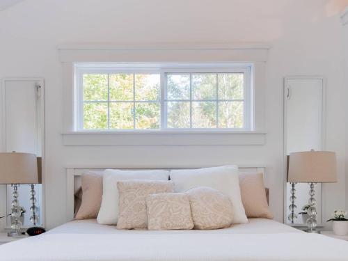 a white bed with pillows and a window above it at Mahone Bay Hide-Away in Mahone Bay