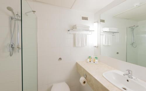 a white bathroom with a sink and a shower at Copthorne Hotel Auckland City in Auckland