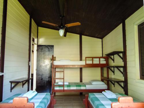 a room with two bunk beds and a ceiling fan at Chalés Aguaí in Natal