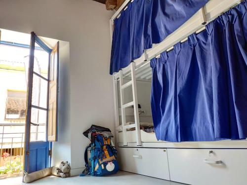 a bunk bed with a blue curtain and a backpack at Albergue Casa de los Hidalgos - Sólo para Peregrinos in Hospital de Órbigo