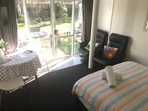 a bedroom with a bed and a table and a window at Sandy Feet Accommodation in Christchurch
