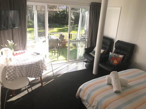 a bedroom with a bed and a table and a balcony at Sandy Feet Accommodation in Christchurch